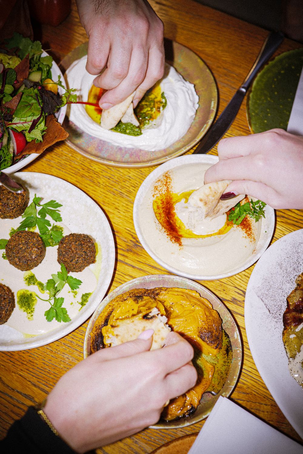 Een tafel vol gedeelde mezzes met handen die toeschieten