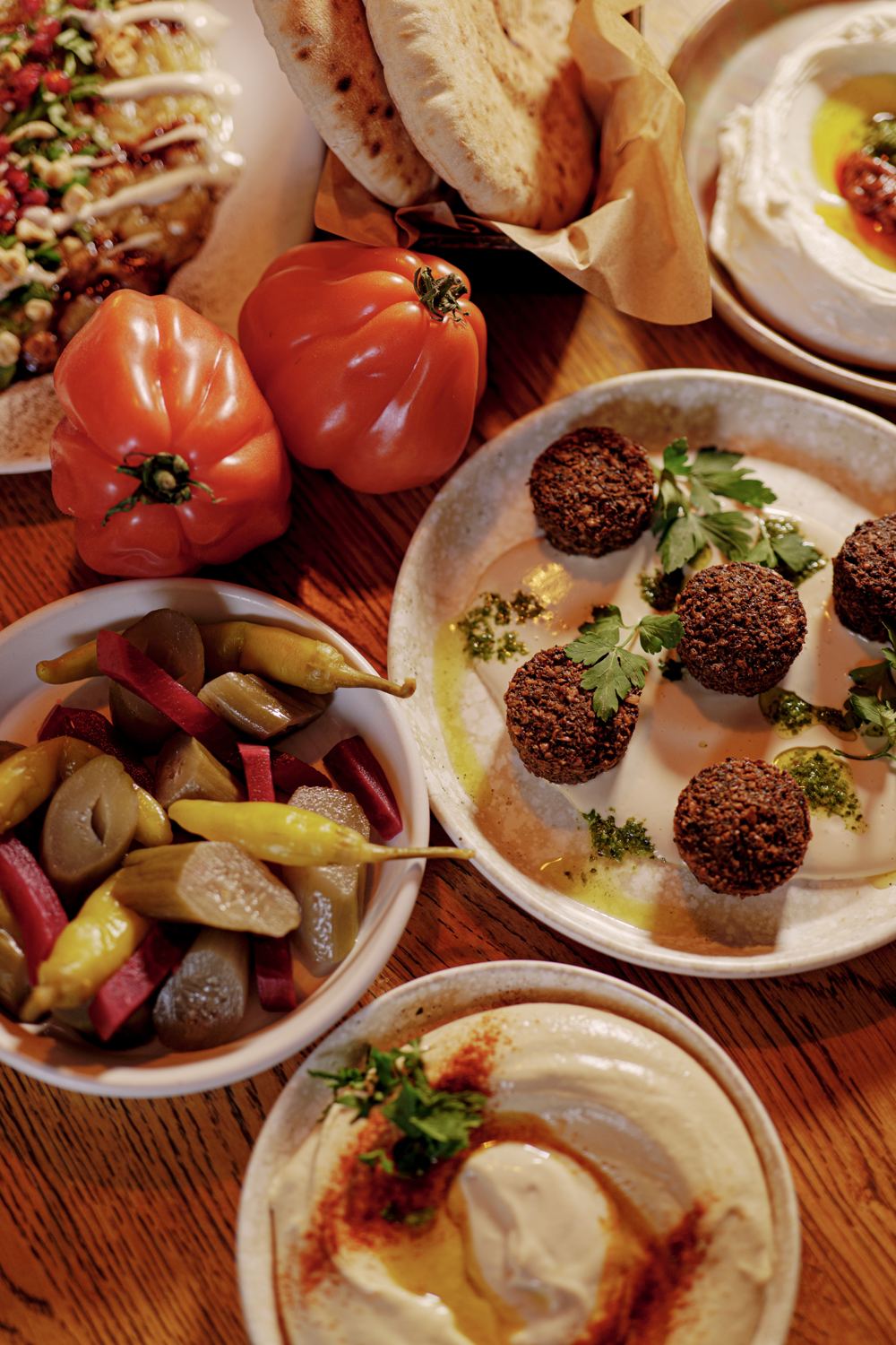 Een tafel vol mezzes: falafel, hummus, tomaten en ingelegde groenten