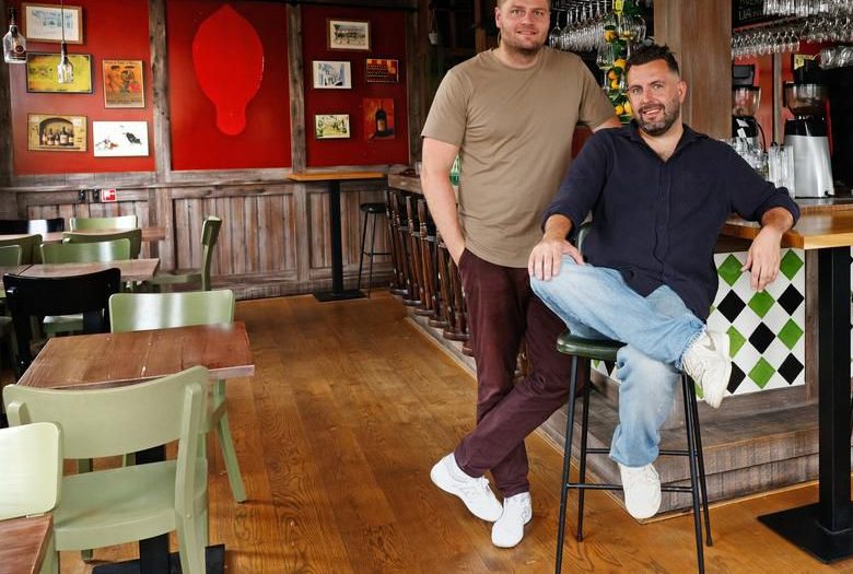 Koen en David aan de bar van het oude Vida, met groene stoelen en rode wanden